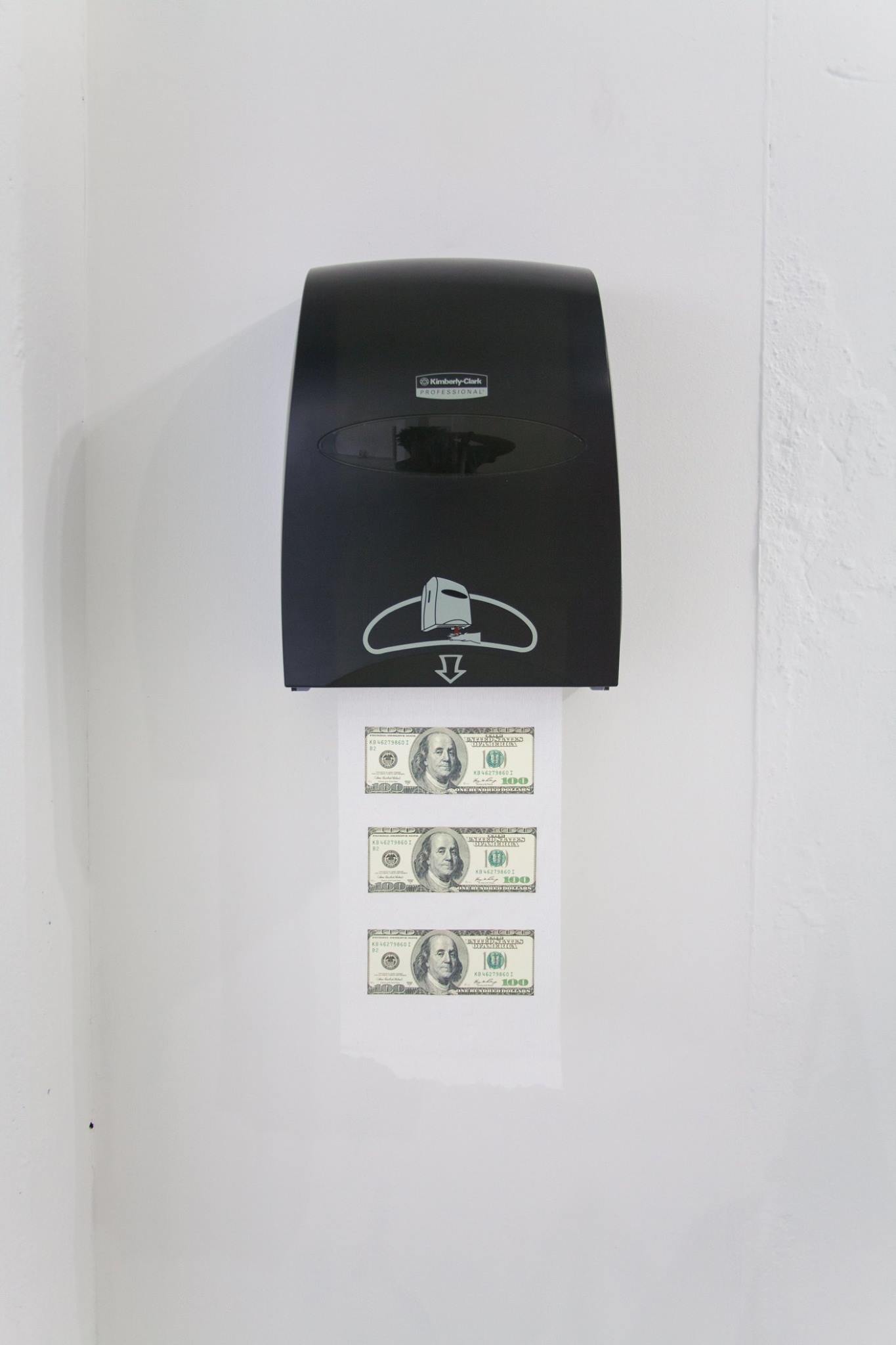 Image of a paper towel with three $100 bills glued to it coming out of a dispenser hung on a white wall